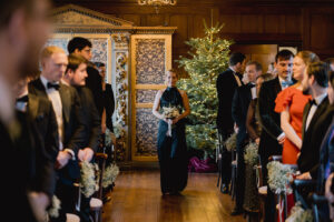 Bridesmaid walking down the aisle at Ramster Hall during a Christmas wedding venue celebration