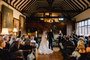 Winter wedding ceremony inside Ramster Hall country house wedding venue with candlelight and greenery