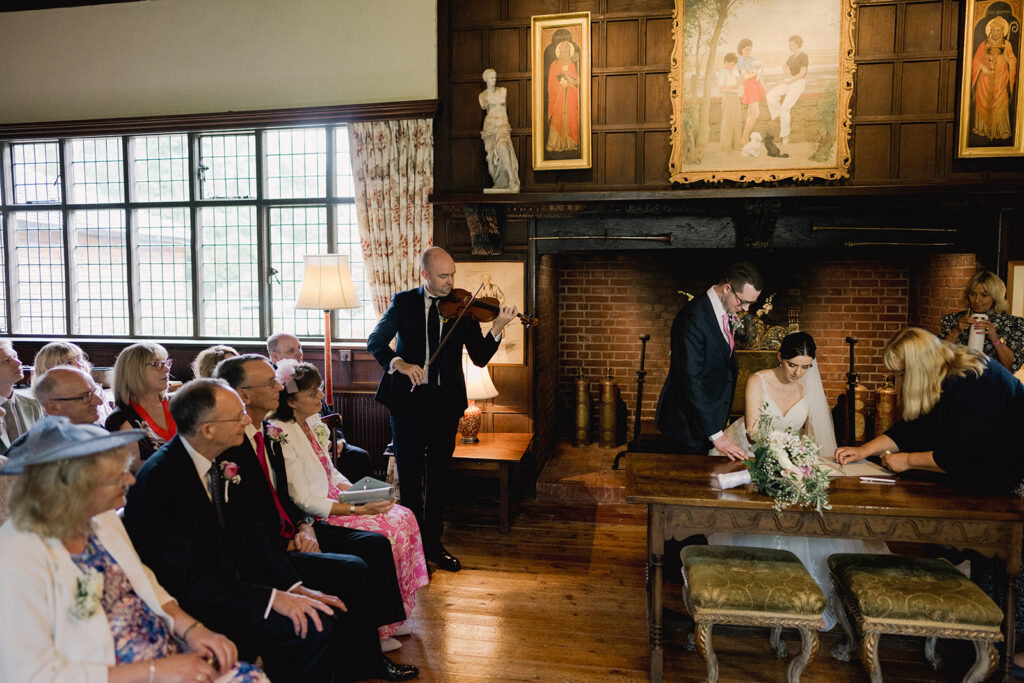 Bride's brother plays during her civil ceremony at a historical venue in Surrey